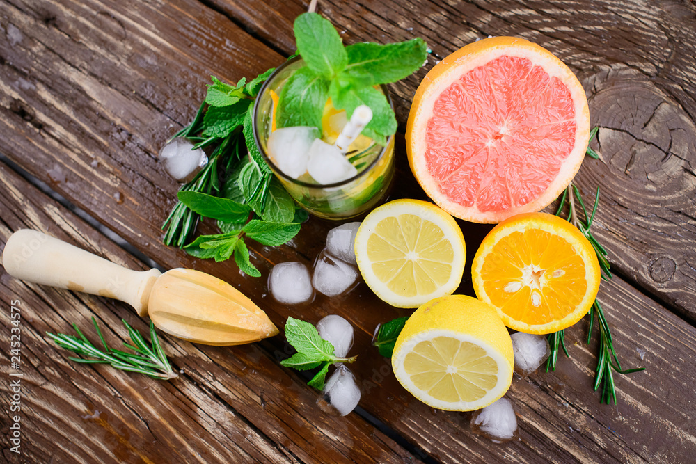 Lemonade with citrus, rosemary and ice on a wooden table. Summer concept. Lemonade with citrus, rosemary and ice on a wooden table. Summer concept.