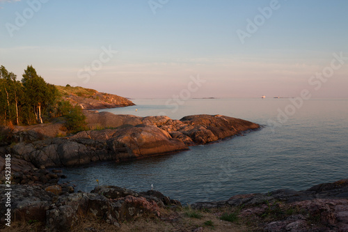 The rocky shore of the island of Suomenlinna and the sea view in the Gulf of Finland at sunset on a summer evening in Finland.