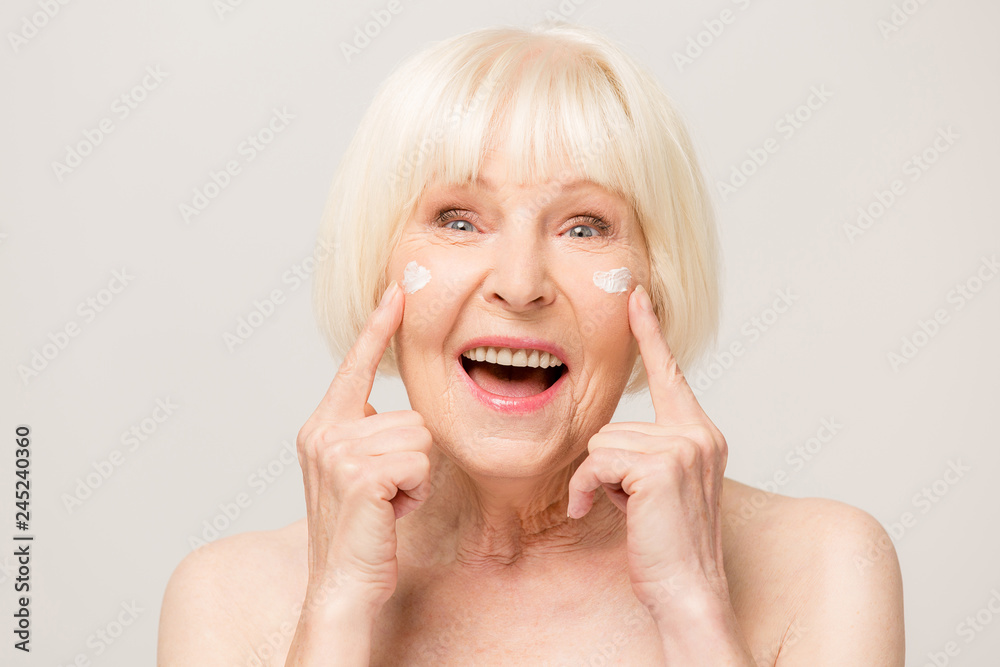 Charming, pretty, old woman touching her perfect soft face skin with ...