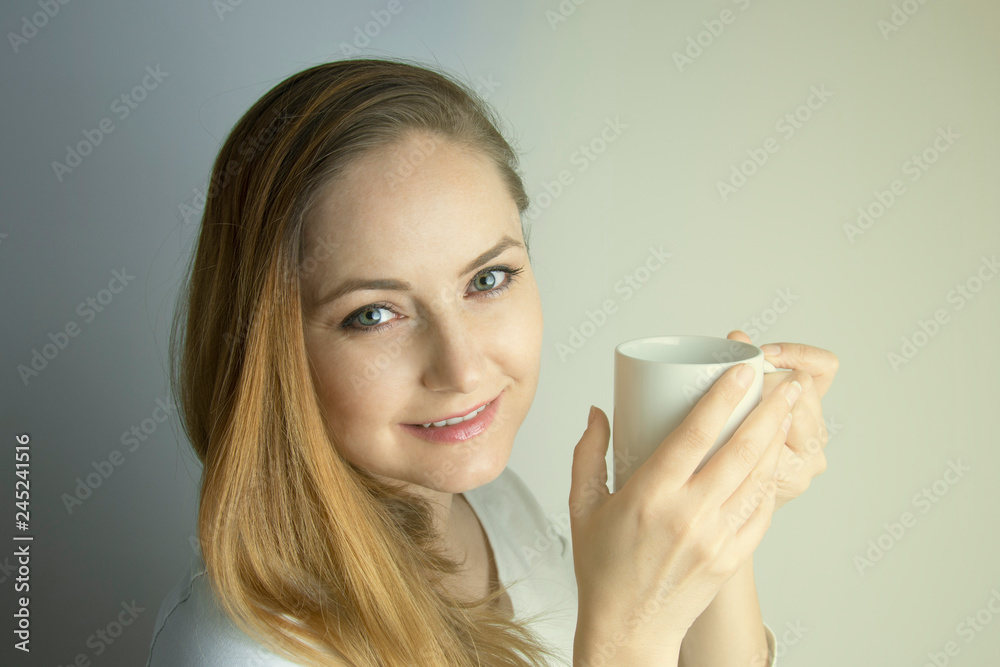 Young woman i nthe morning, holding cup of tea indoors. Portrait of young girl, woman with cup of hot drink. Young woman i nthe morning, holding cup of tea indoors. Portrait of young girl, woman with cup of hot drink.