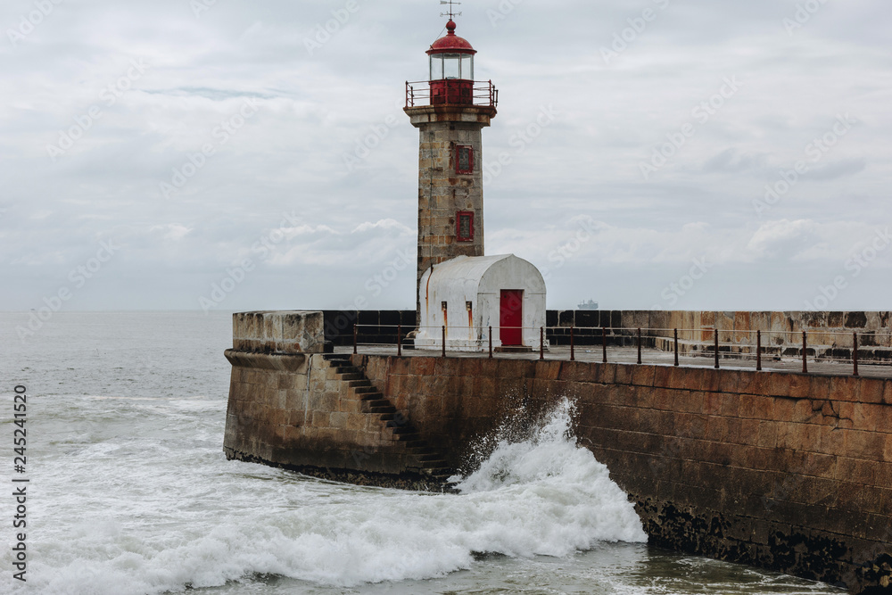 Old lighthouse and granite pier at the mouth of Douro river, Porto