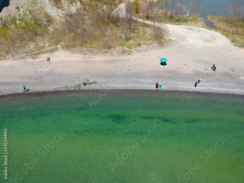 Aerial view of the sand beach in lake Ontario, Toronto, Canada. Bird eye view of sandy beach with few people in the bay with transparent blue water at sunny day Top view. Landscape.