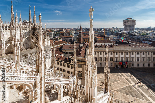 Top view from the roof of Duomo di Milano Cathedral with marble statues to the city and the Royal Palace Palazzo Reale on Piazza del Duomo square. Milan, Italy.