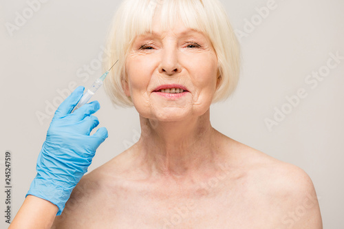Senior woman getting skin care injection. Aged lady having botox injecting procedure. Cosmetic treatment with injection in a clinic.