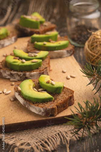 bruschetta with chopped avocado, olive oil, and seeds of seeds and sesame. Healthy vegetarian breakfast on wooden background, healthy nutrition and healthy food.