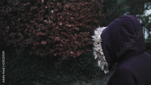 Woman in a purple coat wlaking down a hill slighty to the left of the frame photo