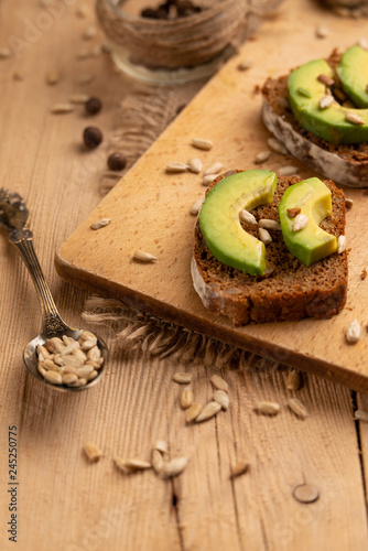 Fototapeta Naklejka Na Ścianę i Meble -  bruschetta on a wooden background with avocado and seeds of shooting, olive oil. Background for design, healthy and clean nutrition. Vegan food