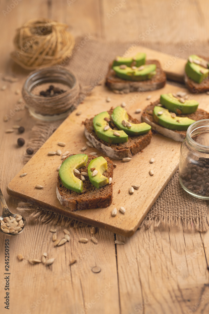 bruschetta on a wooden background with avocado and seeds of shooting, olive oil. Background for design, healthy and clean nutrition. Vegan food bruschetta on a wooden background with avocado and seeds of shooting, olive oil. Background for design, healthy and clean nutrition. Vegan food