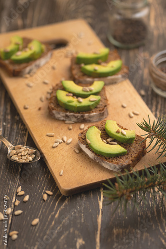ciabatta toasts, bruschetta with chopped avocado, olive oil, and seeds of sesame and sesame. Healthy vegetarian breakfast on wooden background