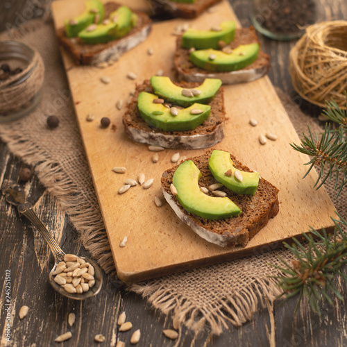 bruschetta with chopped avocado, olive oil, and seeds of seeds and sesame. Background for design. Healthy vegetarian breakfast on wooden background, healthy nutrition and healthy food.