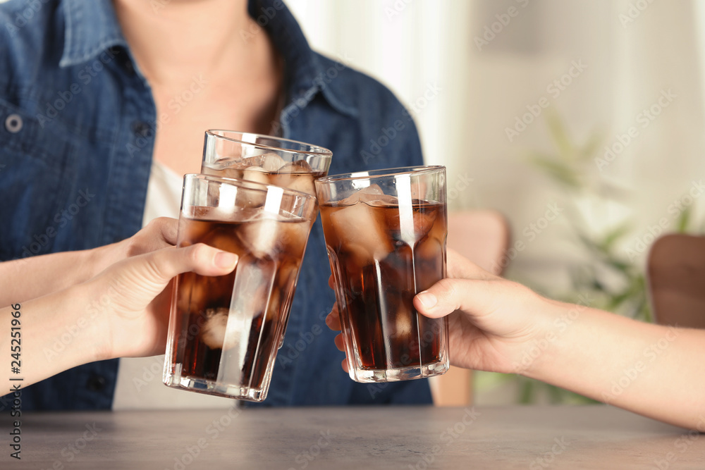 Friends with glasses of tasty refreshing cola at table, closeup view