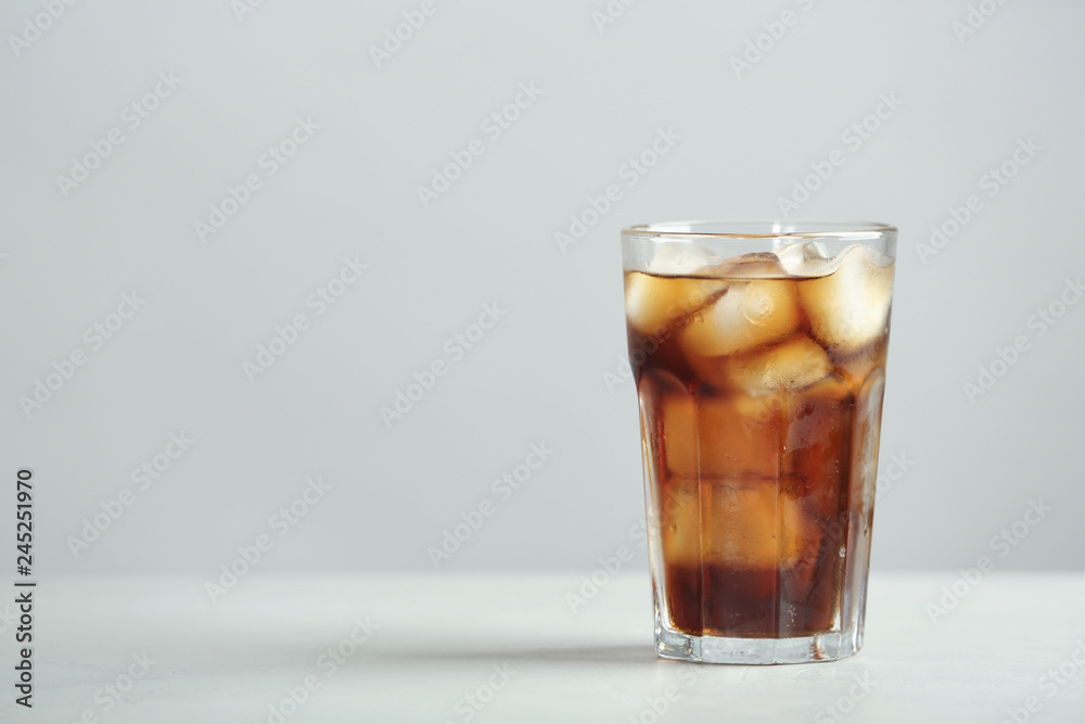 Glass of refreshing cola with ice cubes on table. Space for text Glass of refreshing cola with ice cubes on table. Space for text