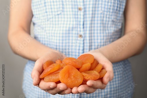 Woman holding handful of dried apricots, closeup. Healthy fruit