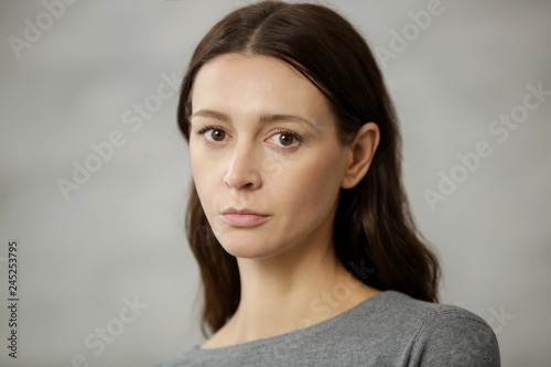 Studio portrait of young caucasian woman looking at the camera, grey background