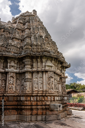 Belavadi, Karnataka, India - November 2, 2013: Veera Narayana Temple. the North One of three brown-stone Vimana shrines and towers of the complex under cloudscape. Covered by sculptures.
