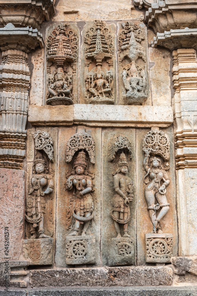 Belur, Karnataka, India - November 2, 2013:  Chennakeshava Temple. Large Brown wall stone side panel sculpture of, top row, Vishnu and his two wives, bottom row, Shilabalikas, dancing girls.