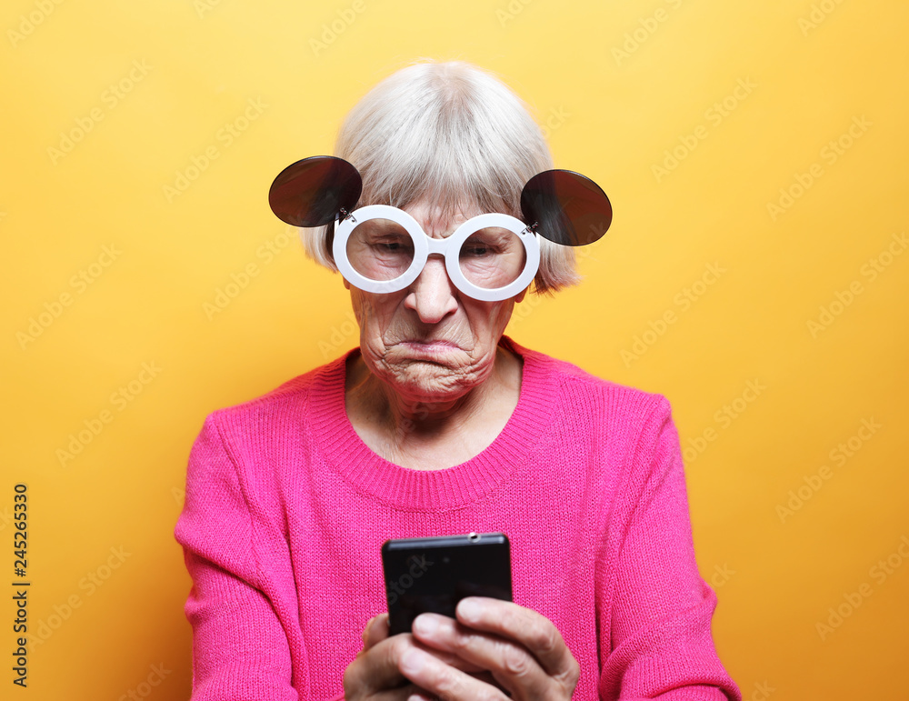 Fototapeta premium old grandmother is talking to her grandchildren by phone, smiling and greeting them.