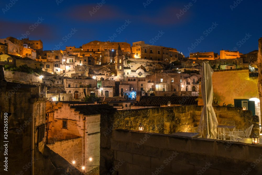 Evening view of the ancient city of Matera, with the colored lights highlighting patios of sidewalk cafes and churches in the historic village in the Basilicata regio
