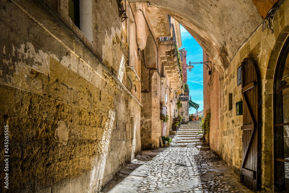 A covered alley leads to a cafe and piazza in the ancient city of Matera, Italy