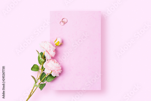 A romantic love letter that is yet to be written with wedding rings and rose on pink background. Flat lay image with copy space. © twenty2photo