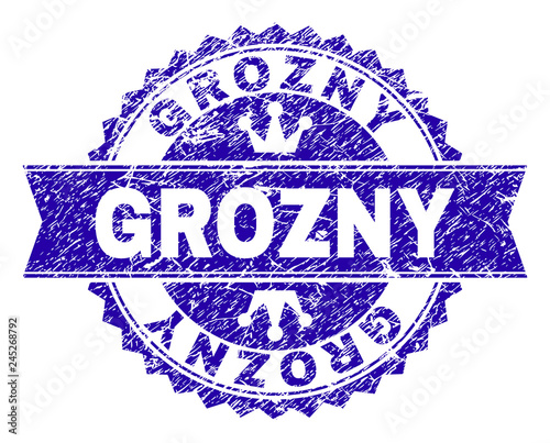 GROZNY rosette seal watermark with grunge texture. Designed with round rosette, ribbon and small crowns. Blue vector rubber watermark of GROZNY text with dust texture.