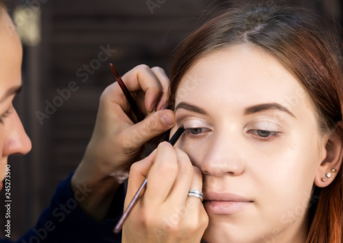 makeup artist preparing young beautiful woman. close-up eyeliner