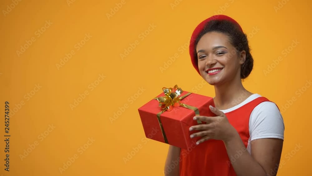 Funny woman rejoicing, dancing with received present, isolated yellow background Funny woman rejoicing, dancing with received present, isolated yellow background