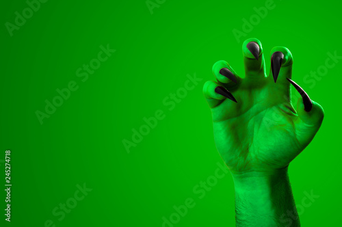 Obraz na płótnie Halloween, nightmare creature and evil monster horror story concept with a scary zombie or demon hand with creepy long black nails isolated on green with a clip path cutout and copy space w salonie