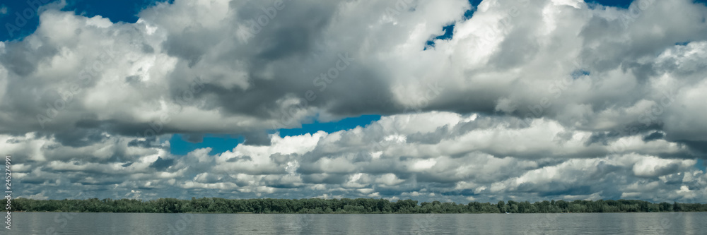 Big white clouds on the blue sky above the river. Big white clouds on the blue sky above the river.