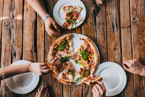 Εκτύπωση καμβά Hands grabbing pizza carbonara on rustic wooden table