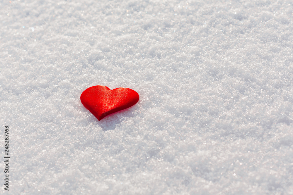 Red heart on glittering snow. Vilentine's day theme. Copy space