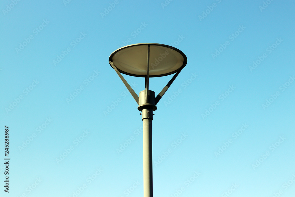 A round street lamp against the blue sky