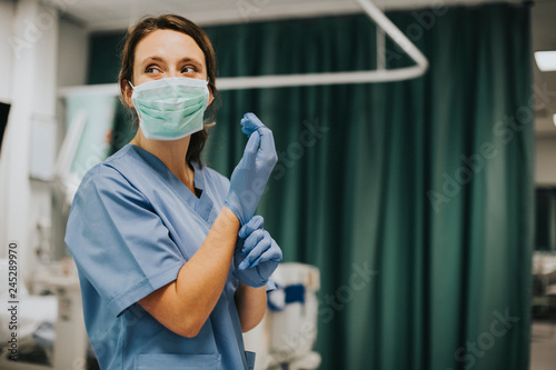 Tela Nurse putting on gloves in hospital room