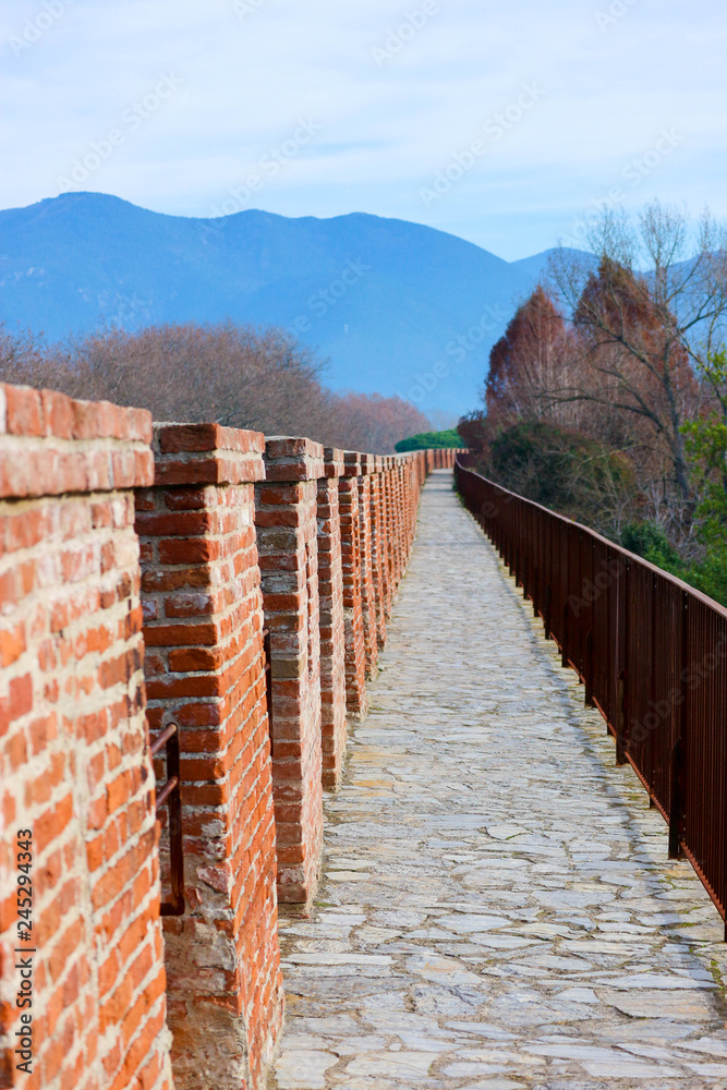 Red brick Pisa city wall walkway with Tuscany mountains on the background, Italy