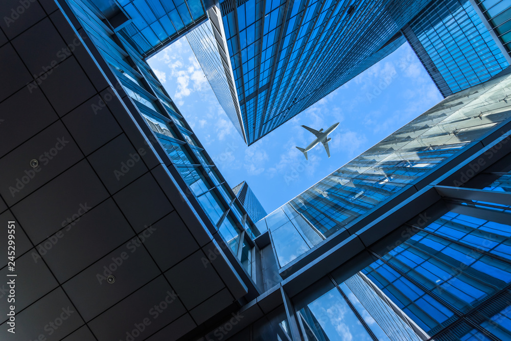 Tall city buildings and a plane flying overhead. Tall city buildings and a plane flying overhead.