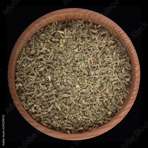 seeds of anise  in wooden cup isolated on black background. top view