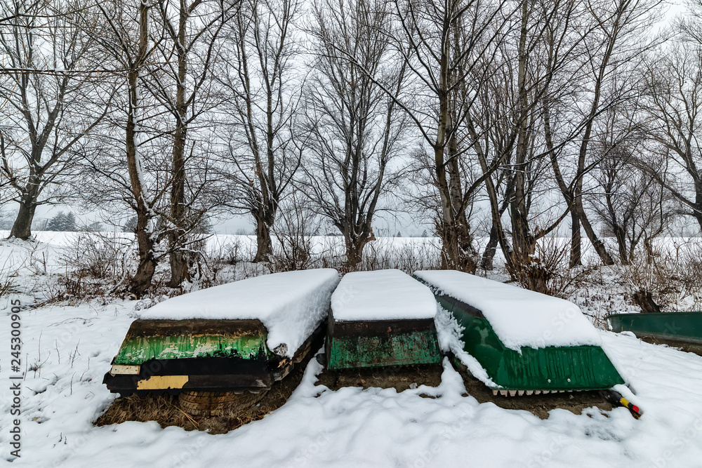 Naklejka premium A boats covered with snow on the coast