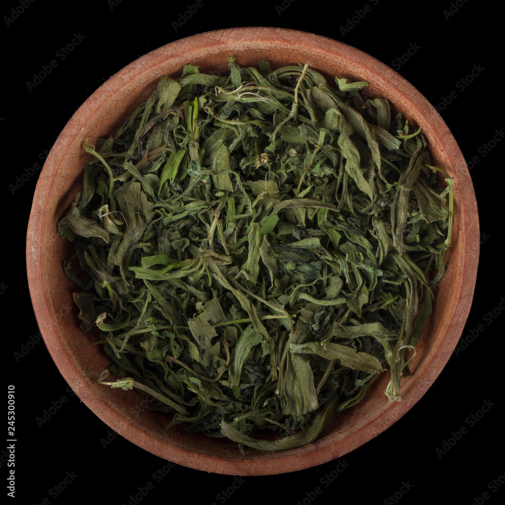 dried estragon in wooden cup isolated on black background. top view dried estragon in wooden cup isolated on black background. top view