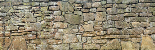 Panorama einer groben, sehr alten Natursteinmauer aus unterschiedlich großen Steinen photo