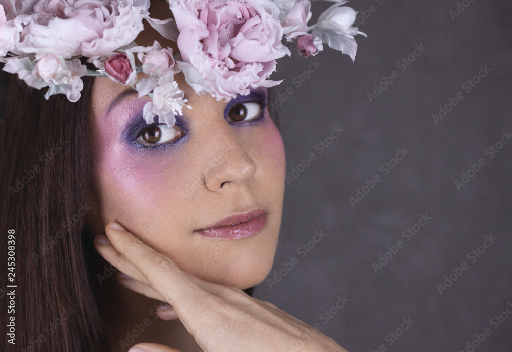 Fashion Portrait of Young Woman with Beautiful Flower Wreath Hairstyle and Fashion creative Makeup.