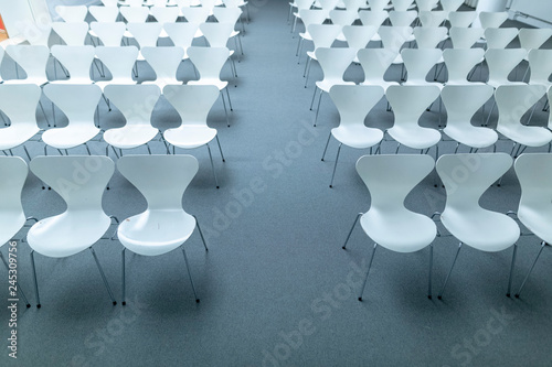 viele weiße Plastikstühle in einem Saal photo