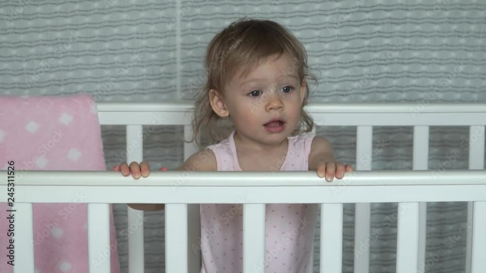 Little beautiful baby girl playing in her white crib. Laughs and smiles Little beautiful baby girl playing in her white crib. Laughs and smiles