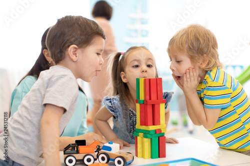 Little kids build wooden toys at home or daycare. Emotional kids playing with color blocks. Educational toys for preschool and kindergarten children.