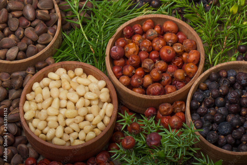 cedar nuts and juniper berries on wooden background