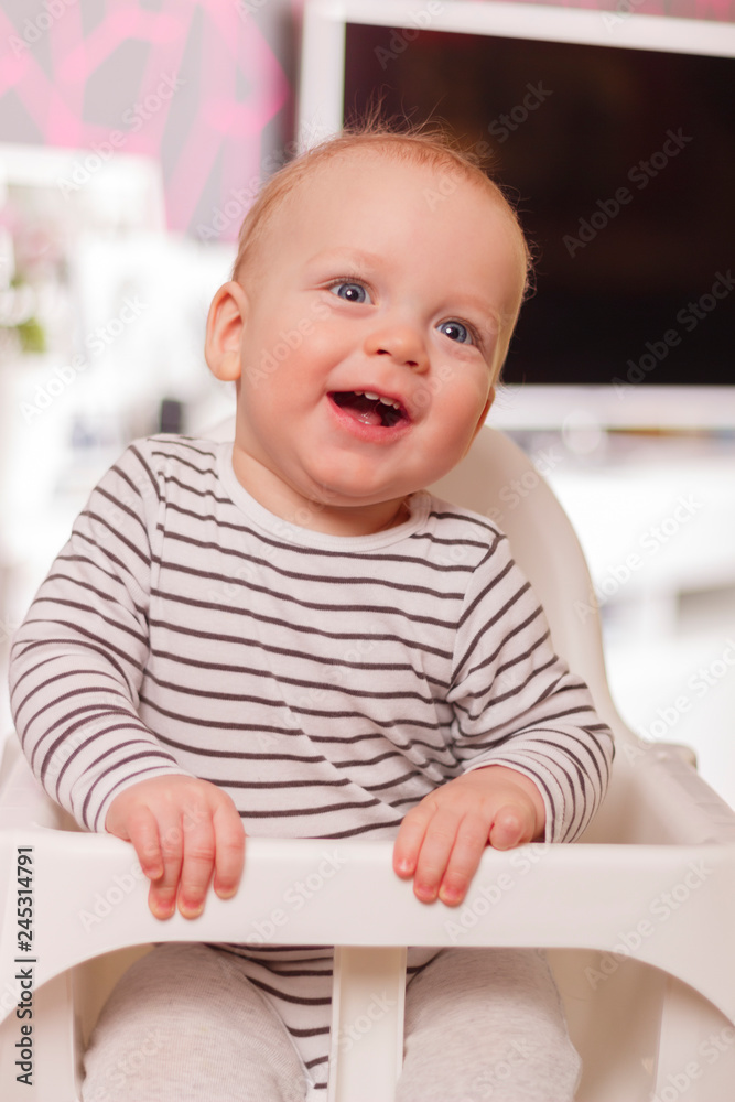 Happy smiling cute toddlersitting in the baby chair. Concept of happiness Happy smiling cute toddlersitting in the baby chair. Concept of happiness