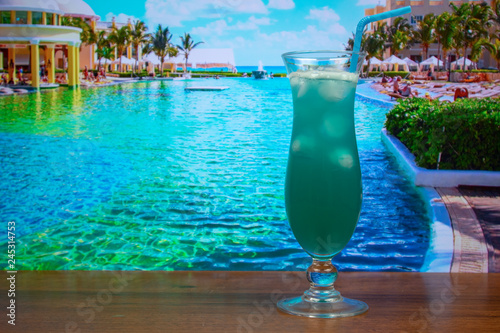 Blue Hawaii cocktail in hurricane glass with a straw and ice
