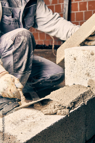 Real construction worker bricklaying the wall indoors.