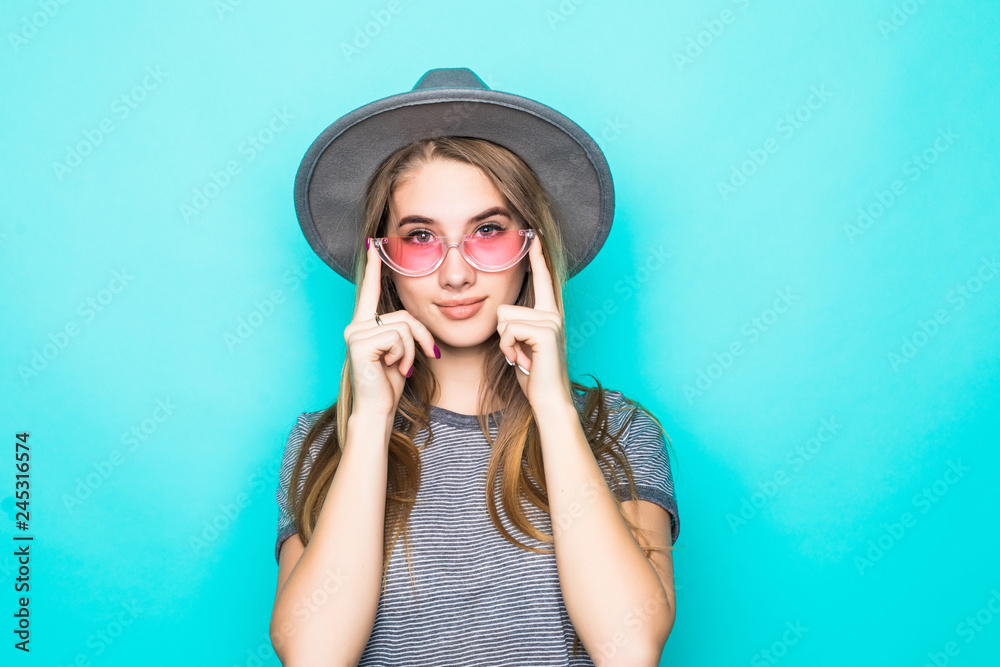Portrait of pretty woman in sunglasses and fluppy hat over blue colorful background Portrait of pretty woman in sunglasses and fluppy hat over blue colorful background