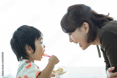 プリンを食べる男の子と見守る母親