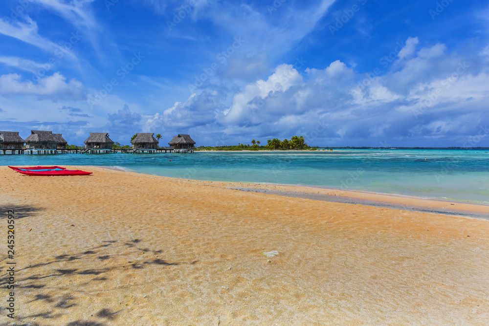 Fototapeta premium Coastline with a tropical beach and the turquoise water of the inner lagoon of the atoll of Tikehau at sunny day. Tuamotus archipelago, French Polynesia, south Pacific ocean.